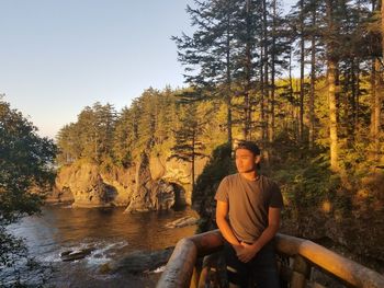 Young man standing at observation point in forest