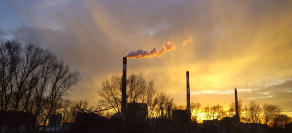 Low angle view of smoke emitting from factory against sky during sunset
