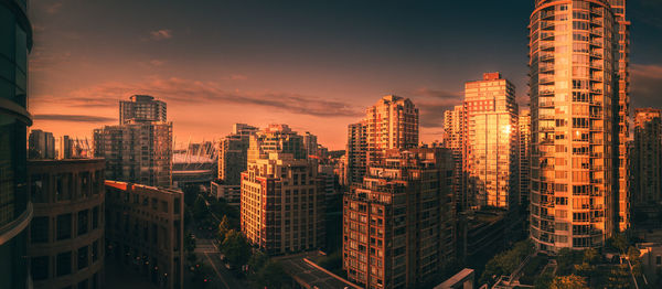 Modern buildings in city against sky during sunset