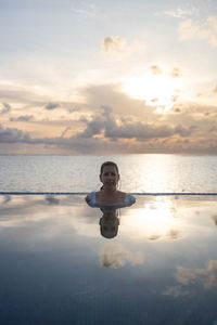 Woman into a infinity swimming pool near the ocean