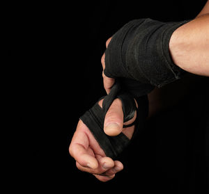 Cropped hands with straps against black background