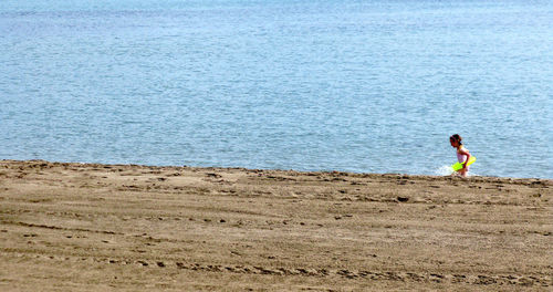 Girl playing at beach on sunny day