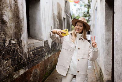 Young woman standing against wall