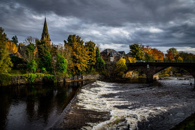 Bridge over river against cloudy sky