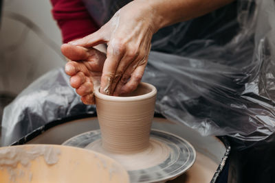 Close up of woman hands molding clay mug spinning on pottery wheel. potter hands forming clay cup