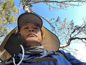 Low angle portrait of man against blue sky