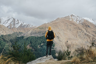 Rear view of man standing on mountain against sky