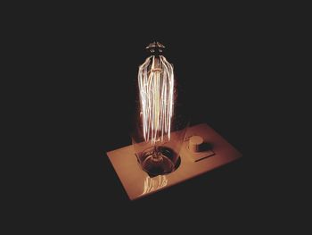 Close-up of illuminated lighting equipment on table against black background
