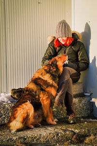 Woman with dog sitting outdoors during winter