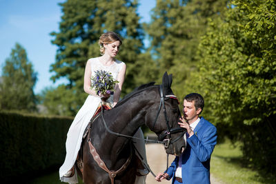 Young bride riding horse on field