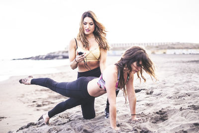 Women exercising on beach against sky