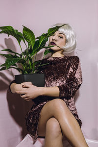 Young woman sitting with pot plant