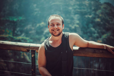 Portrait of smiling young man against railing