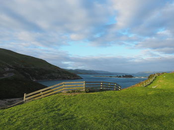Scenic view of landscape by sea against sky