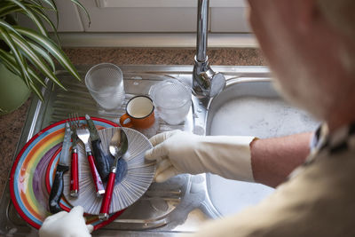 Midsection of senior man cleaning dish at kitchen