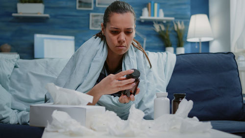 Young woman using mobile phone while sitting at home