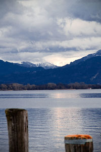 Wooden posts in lake against sky