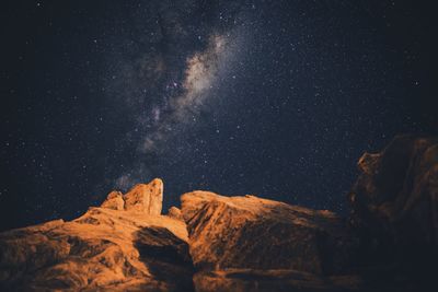 Low angle view of rocks against sky with star field