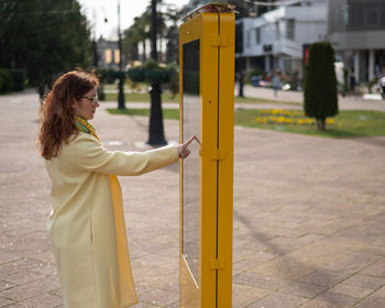 Side view of young woman standing against sky