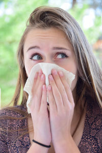 Close-up of teenage girl looking away blowing nose