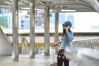 Woman talking on phone while standing by railing