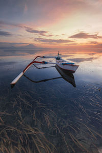 Boat moored on sea against sky during sunset