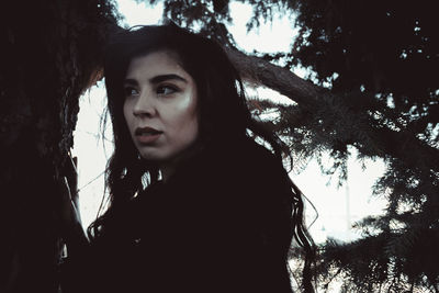 Portrait of young woman against trees