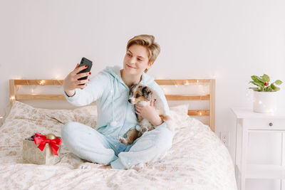 Young woman using laptop while sitting on bed