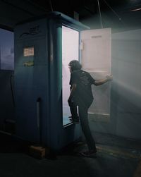 Side view of woman standing against door