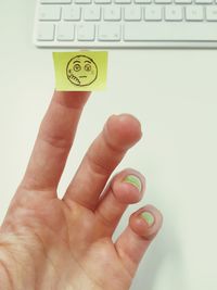 Close-up of cropped hand showing sad face on adhesive note