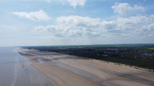 Scenic view of road by sea against sky