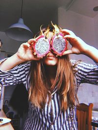 Young woman holding dragonfruit at home