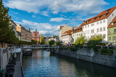 Bridge over canal amidst buildings in city against sky