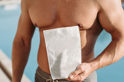 Midsection of muscular man holding paper