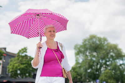 Middle-aged woman with a short haircut with an umbrella protecting from sun