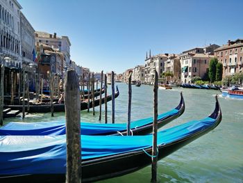 Gondolas moored in canal against buildings