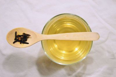 Directly above view of cloves in wooden spoon on drink