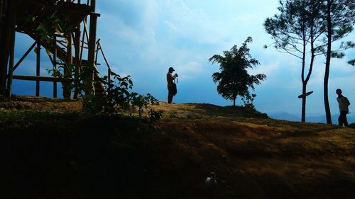 Silhouette man standing by tree against sky