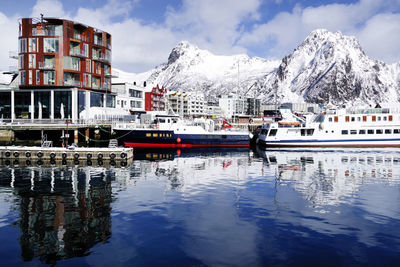 Reflection of building on snowcapped mountain against sky