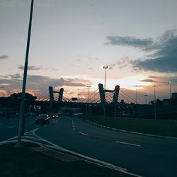 Road by city against sky during sunset