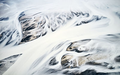 Streams of snow covering mountainous land below