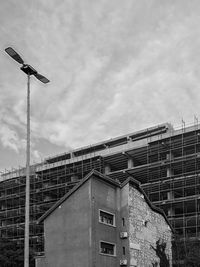 Low angle view of street light by building against sky