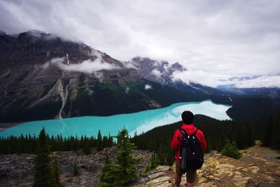 Rear view of man standing on mountain against sky