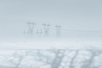 Electricity pylon on field against sky during winter