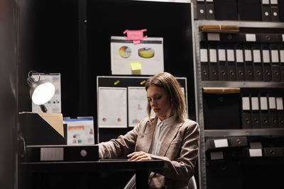 Portrait of young woman using mobile phone in library