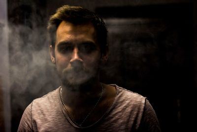 Close-up portrait of young man smoking at home