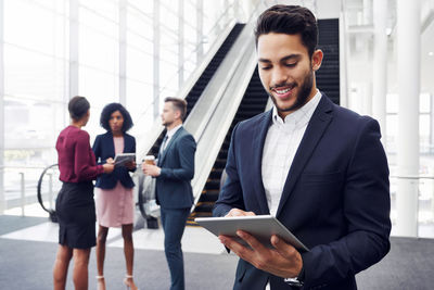 Young man using phone while standing on laptop