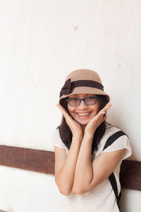 Smiling young woman against wall