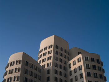 Low angle view of düsseldorf's gehry buildings against clear blue sky