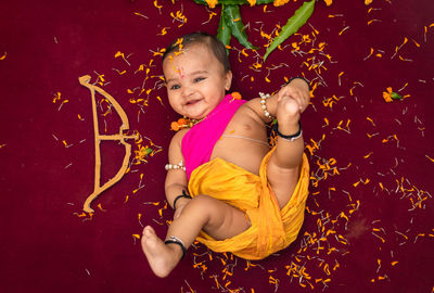 Cute indian boy dresses as lord rama with bow and flowers from top angle